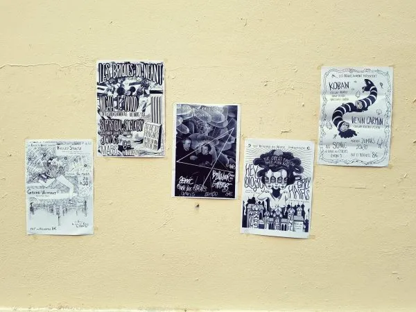 Photo montrant 5 affiches de concert en noir et blanc collées à un mur avec du scotch