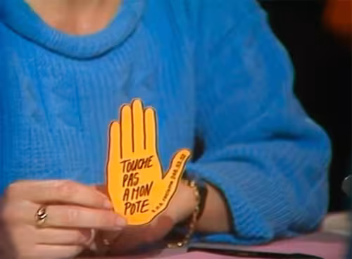 un zoom sur un écran de télé qui montre la main jaune siglée touche pas à mon pote