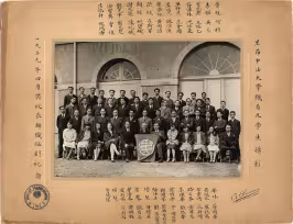 Photo historique en noir et blanc de 1929 représentant le groupe des étudiants et enseignants de l’Institut Franco-Chinois de Lyon, posant devant un bâtiment à arcs en pierre. Environ 60 personnes, hommes et femmes, vêtus de costumes et robes formels des années 1920, sont disposées en rangées. Au centre, un homme tient une bannière avec un emblème circulaire. La photo est encadrée de calligraphies chinoises sur les bords gauche, droit et en bas, avec le tampon officiel Institut Franco-Chinois LYON.